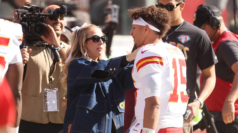 Brittany Mahomes going in for a hug with Patrick Mahomes during a football game surrounded by crowds and cameras