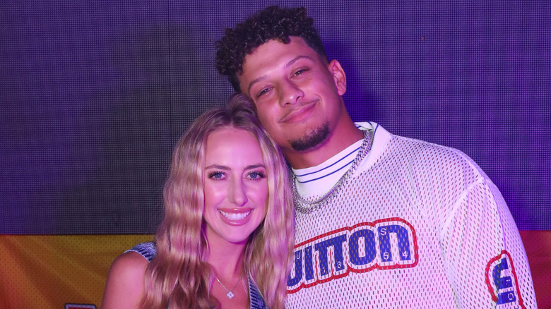 Brittany and Patrick Mahomes leaning into each other posing and smiling for a photo