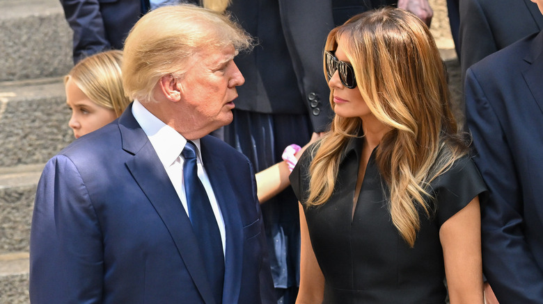 Melania Trump wearing black dress and sunglases with President Donald Trump