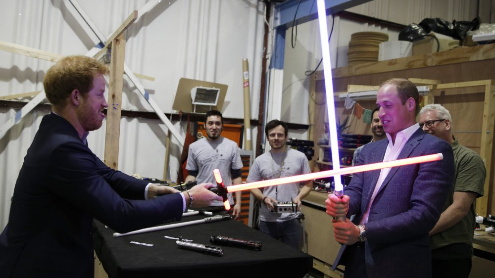 Prince William and Prince Harry holding Star Wars props