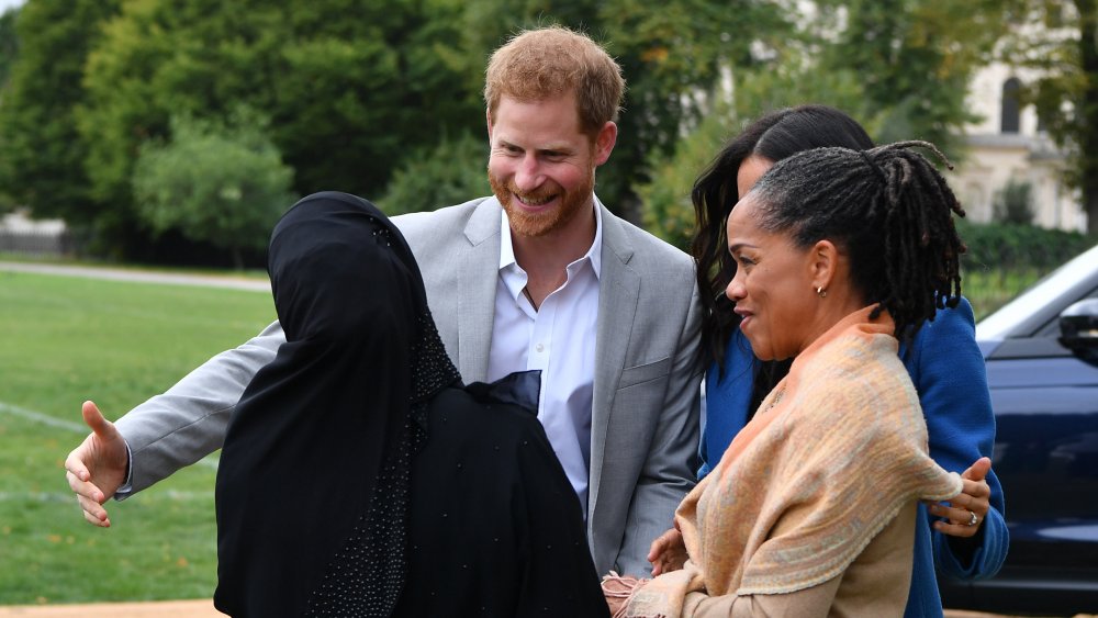 Prince Harry and Meghan Markle greeting a woman