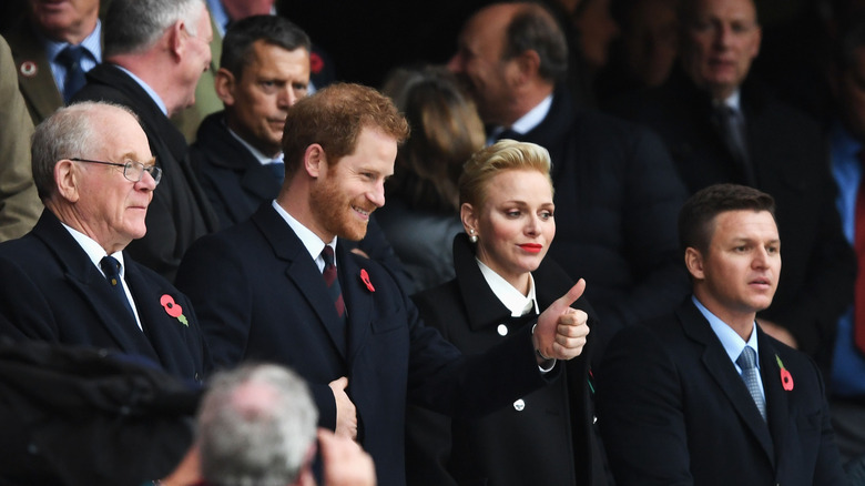 Prince Harry smiling with Princess Charlene in a crowd