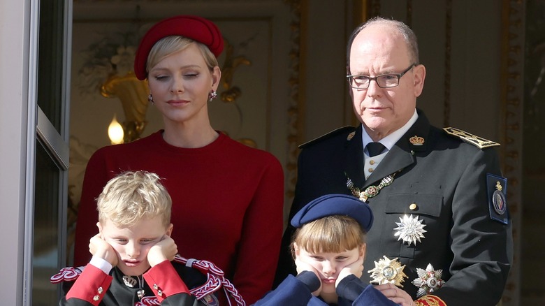 Princess Charlene and Prince Albert standing with their kids on a balcony
