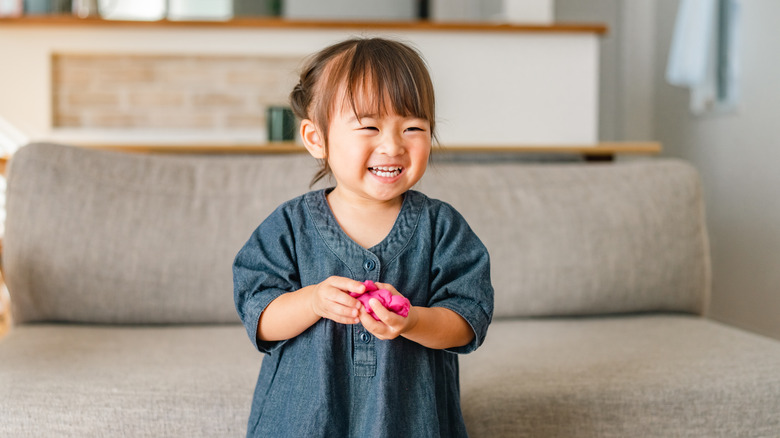 Toddler laughing beside a sofa