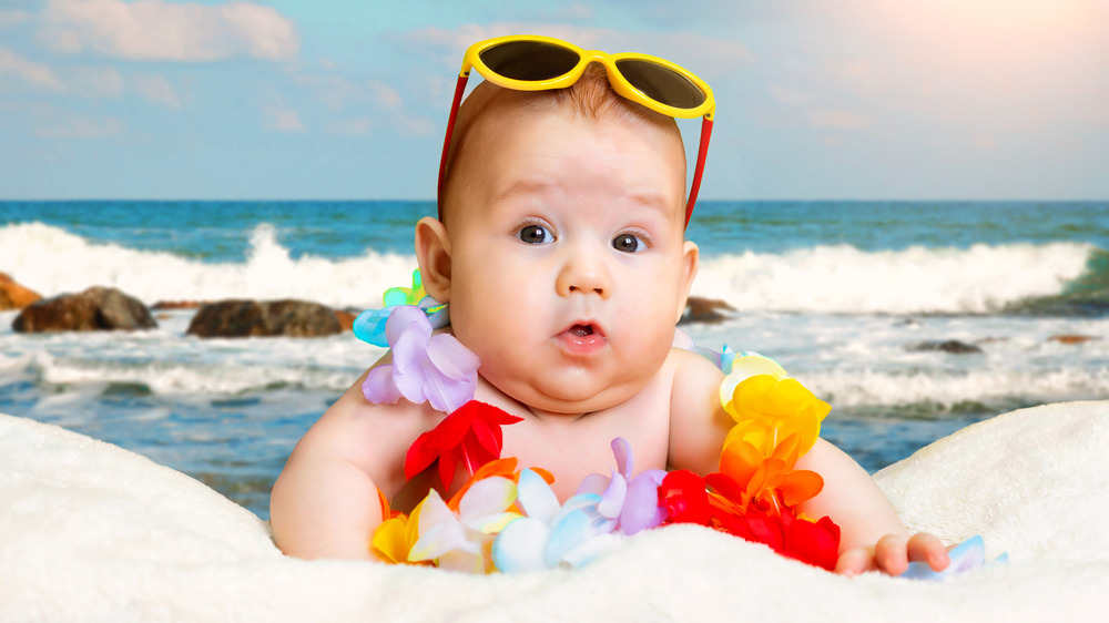 Baby on beach in sunglasses and lei