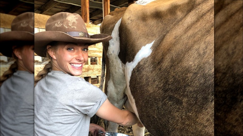 Hannah Neeleman milking a cow wearing cowboy hat