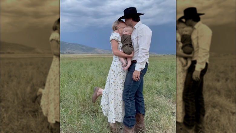 Hannah Neeleman kissing husband in field with baby