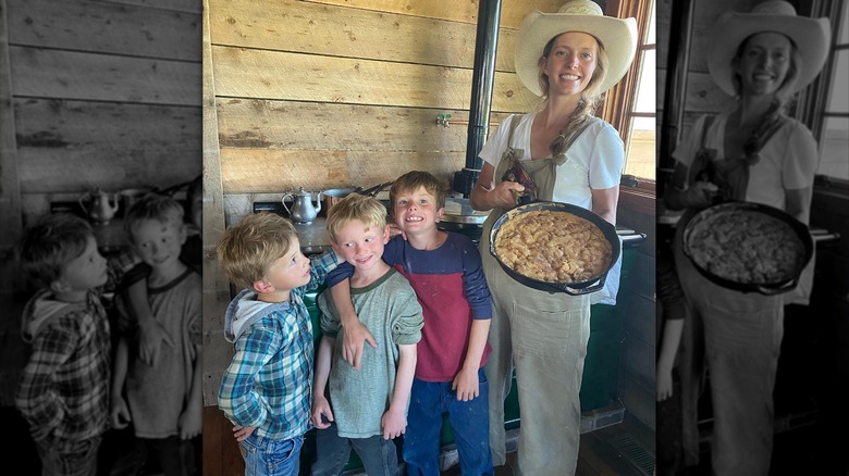 Hannah Neeleman wearing hat and overalls holding pan with three of her sons