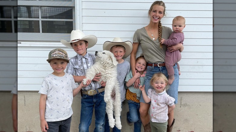 Hannah Neeleman in jeans holding baby with children and  dog