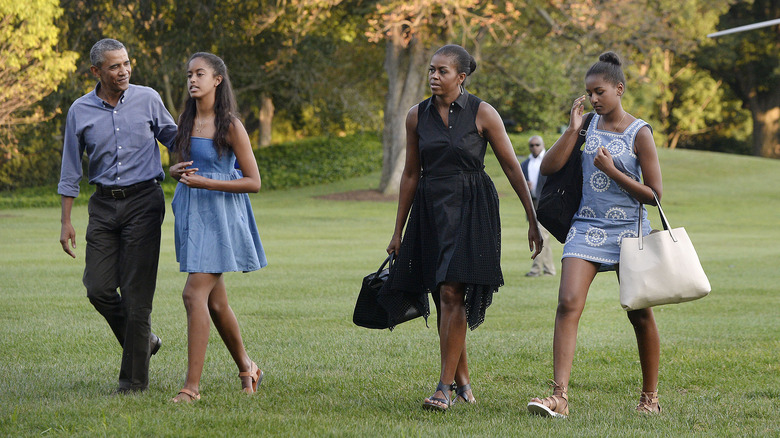 Barack and Michelle Obama walking with their daughters