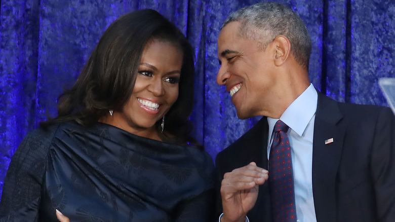 Michelle and Barack Obama leaning in and smiling at each other