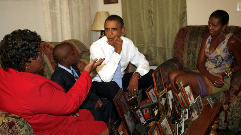 Michelle and Barack Obama sit in living room and talk to homeowners