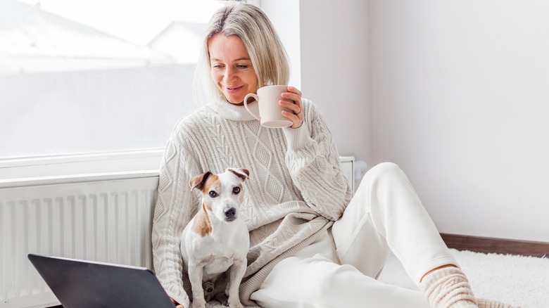 A woman working with her coffee and dog in tow 