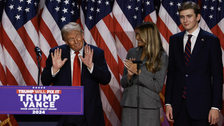 Donald, Melania, and Barron Trump on stage surrounded by U.S. flags