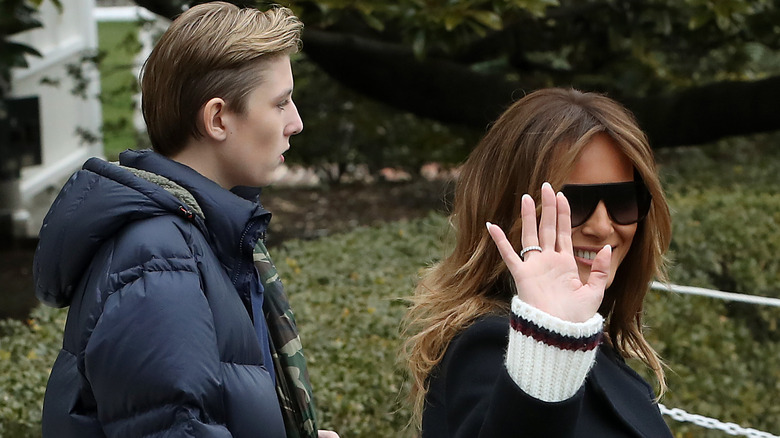 Melania Trump waves while Barron Trump walks behind her