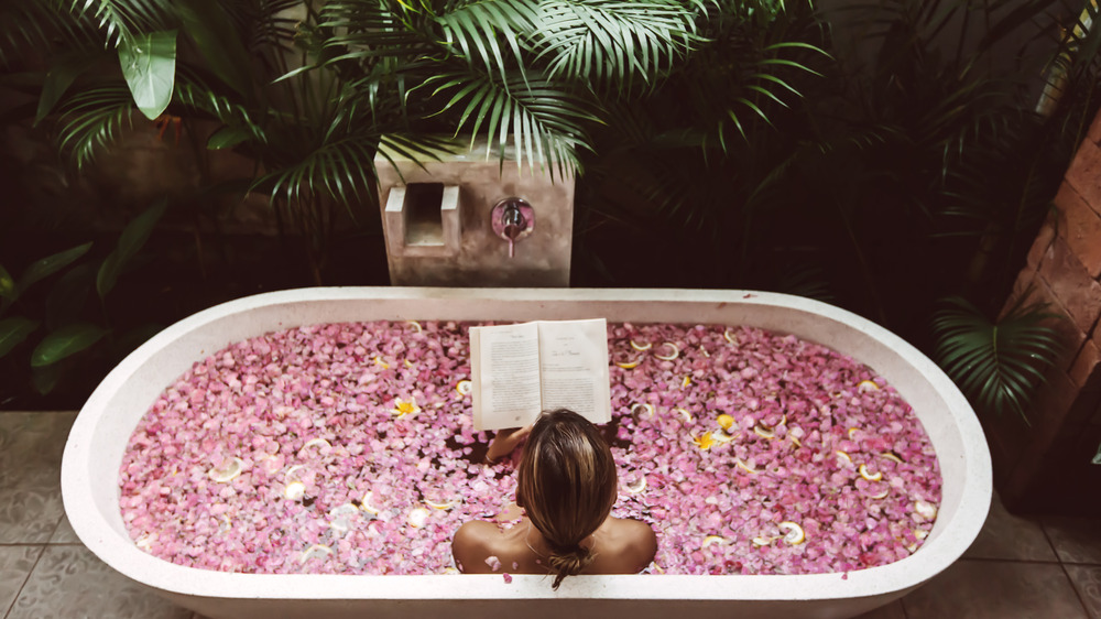 A woman reading a book inside a bathtub