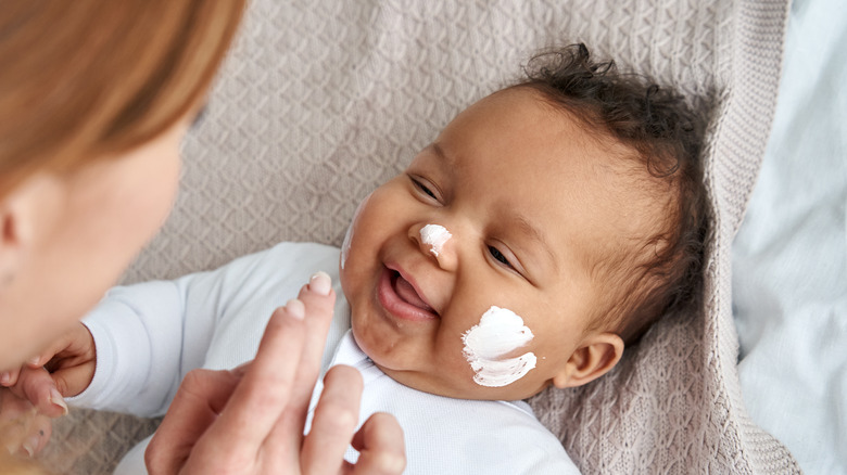 Mother applying cream to baby