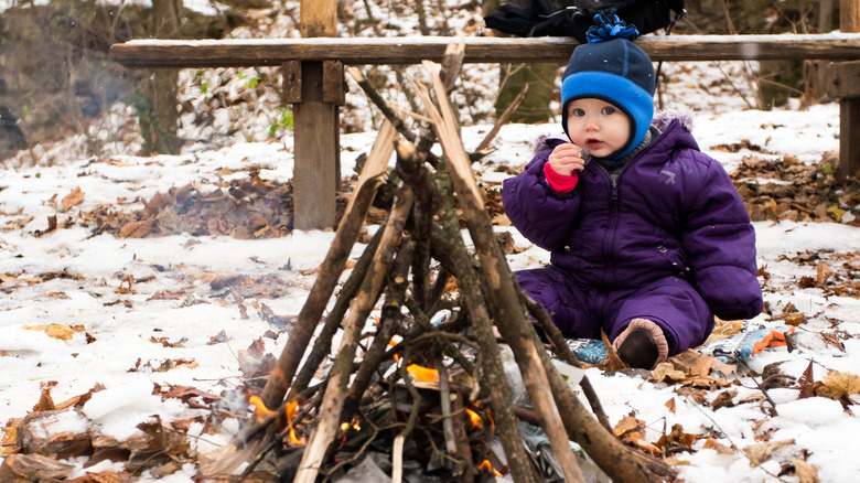 Little girl sitting by the campfire 