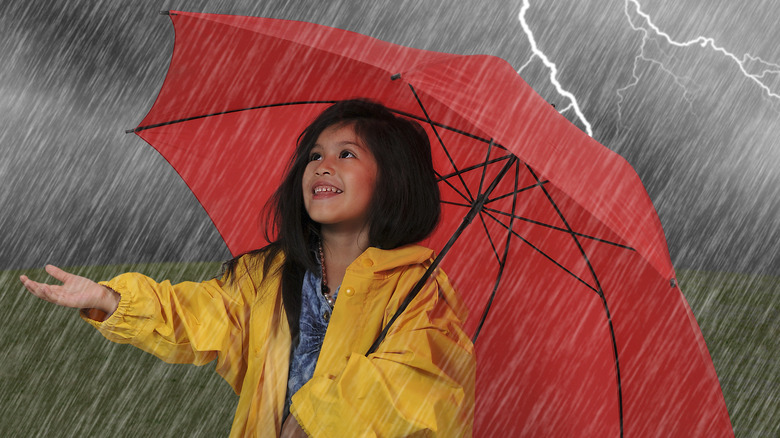 Little girl with umbrella in thunderstorm