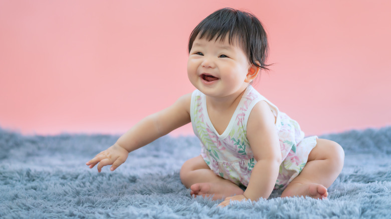 baby smiling on blue carpet