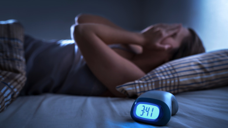 woman in bed with alarm clock