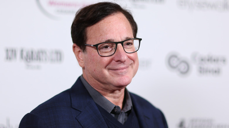 Bob Saget wearing a blue suit and smiling at the camera