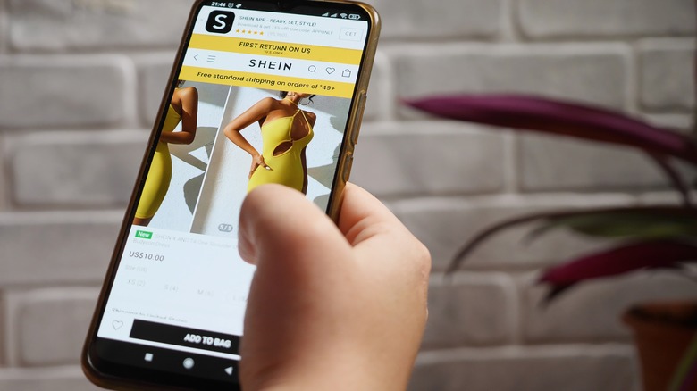Person holding a phone with Shein's website on the screen