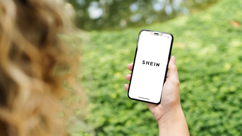 A person holding a phone with Shein on the screen