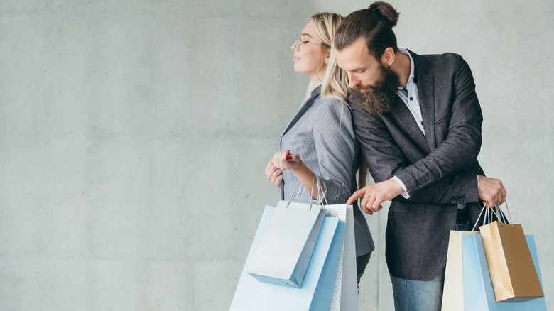 man peeking in woman's shopping bags