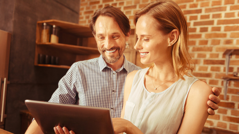 woman showing man something on tablet