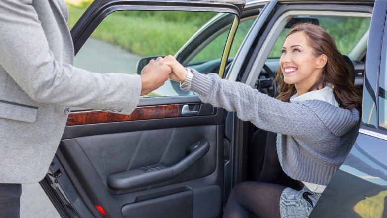 Chivalrous man helping woman out of car