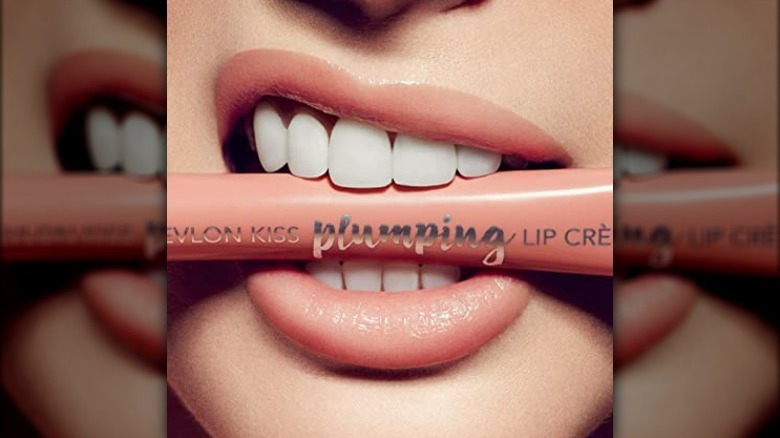 Woman biting Revlon Kiss Plumping Lip Creme