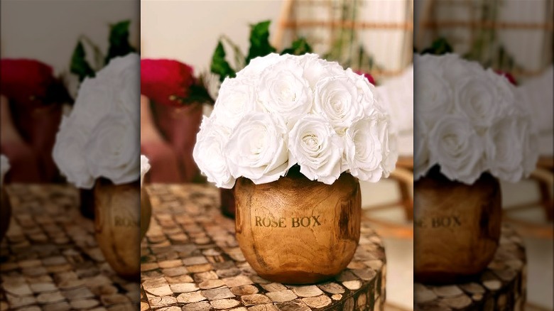 White roses in a round wood vase