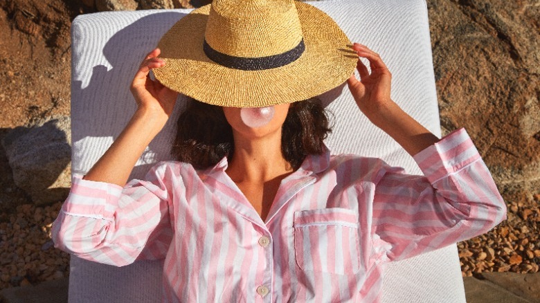 Woman lounging in pajamas wearing large hat