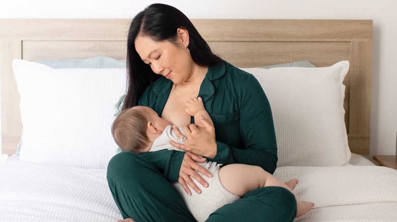 Asian mom wearing pajamas and nursing baby