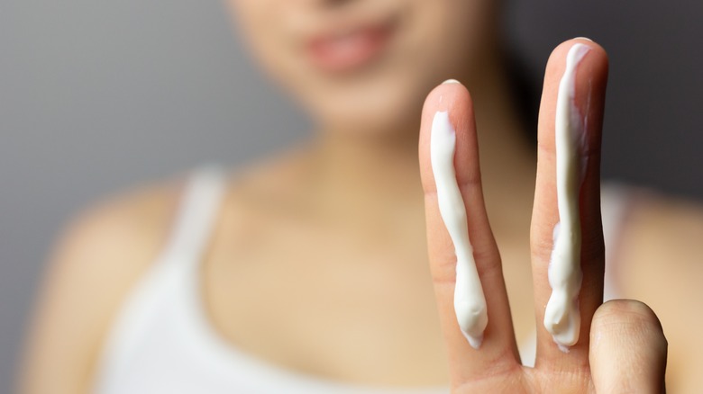 woman with moisturizer on fingers