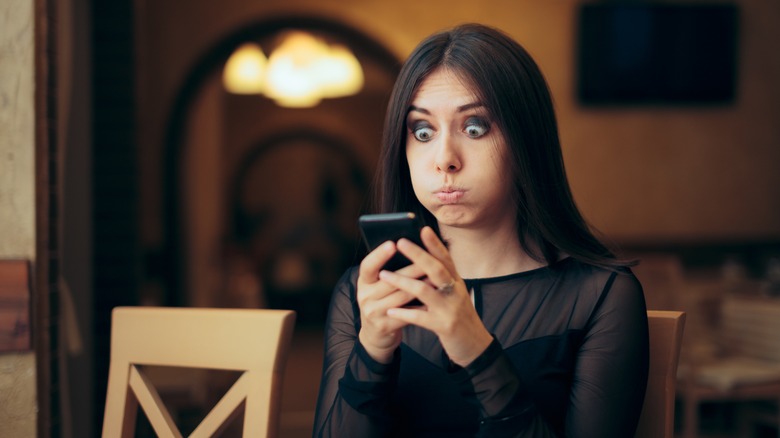 Woman looking at phone shocked