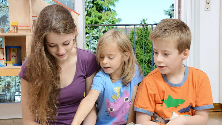 Teenaged babysitter playing with two children