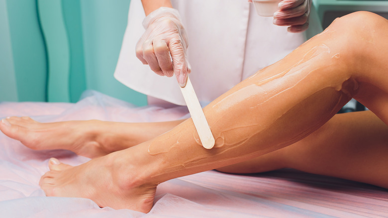 Professional applying wax to person's legs