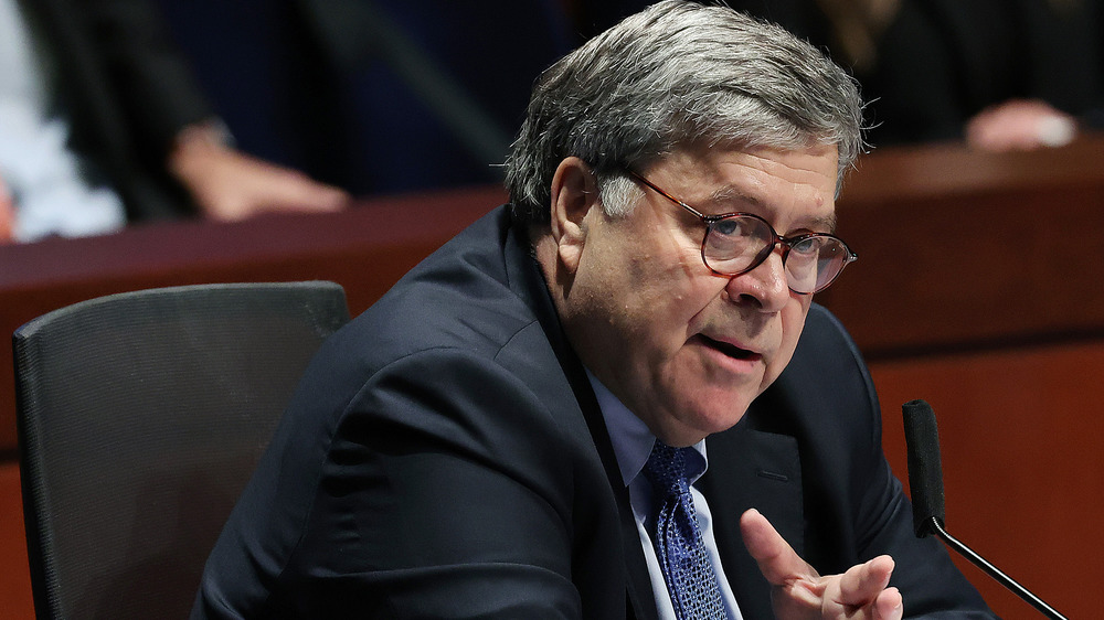 Attorney General Bill Barr sits at a table, talking. 