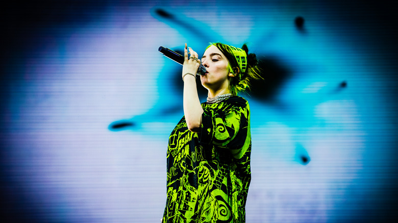 Billie Eilish performing onstage in a green outfit