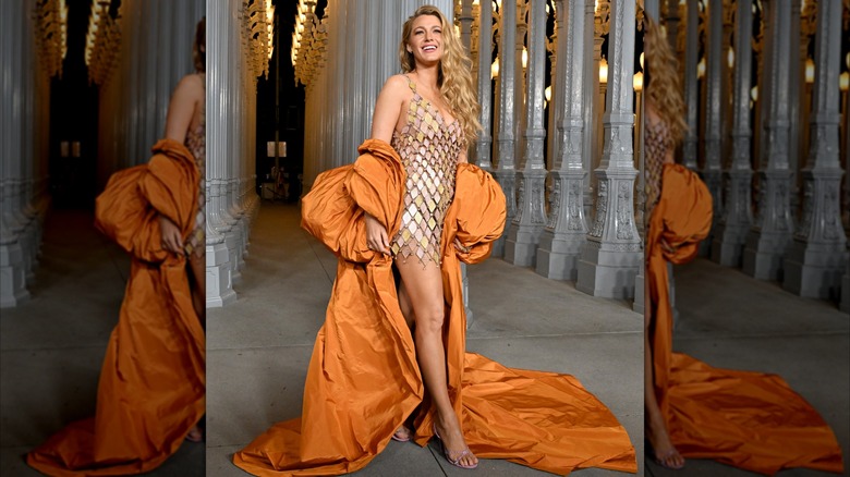 Blake Lively in a short gold dress and big orange cape at the 2024 LACMA Art + Film Gala