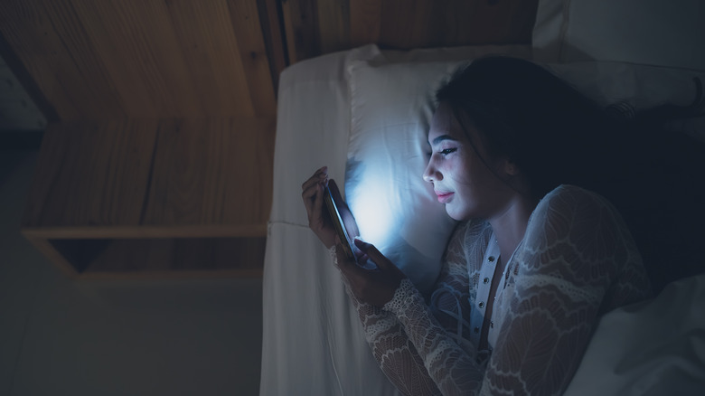 Woman scrolling through social media in bed