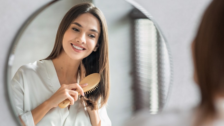 woman brushing brown hair smiling