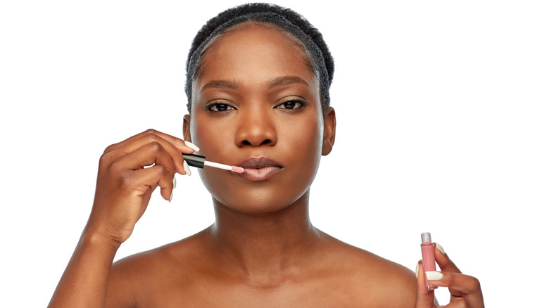 Woman applying lip color with sponge-tip applicator