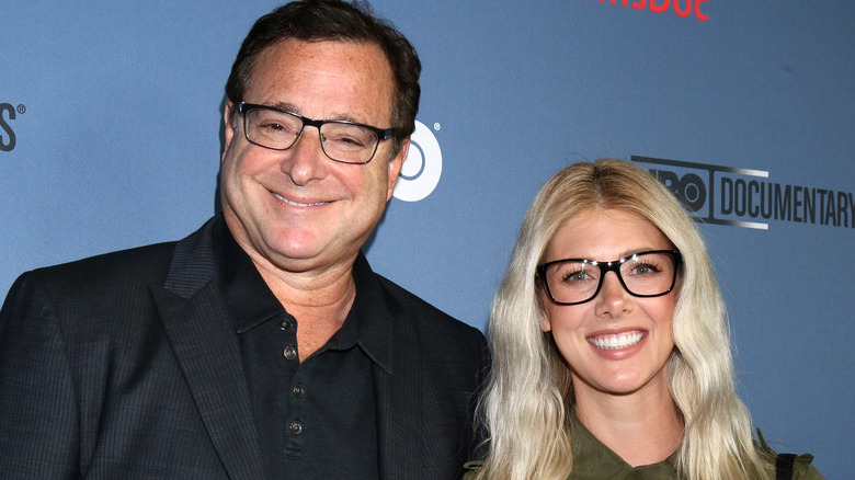 Bob Saget and Kelly Rizzo standing next to each other smiling on the red carpet