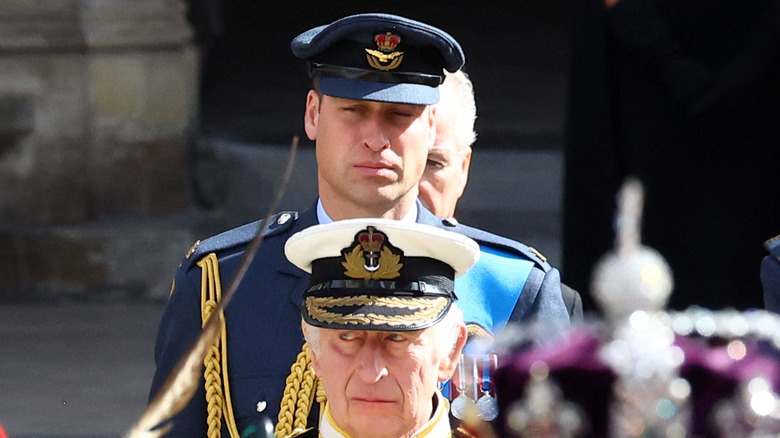 King Charles III walking in front of Prince William 