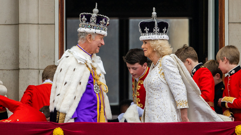 King Charles and Queen Camilla wearing crowns on balcony