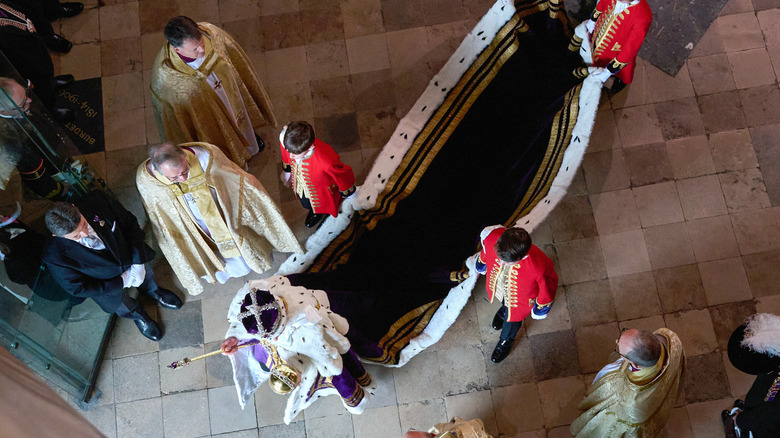 King Charles exiting the coronation as others carry his cape