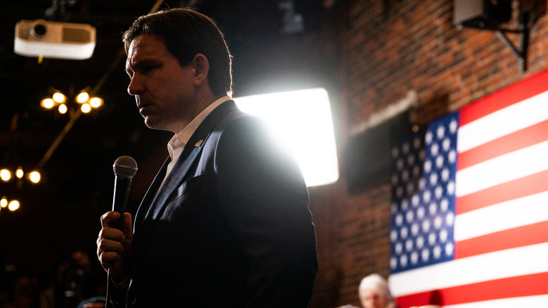 Ron DeSantis looking serious in front of an American Flag 